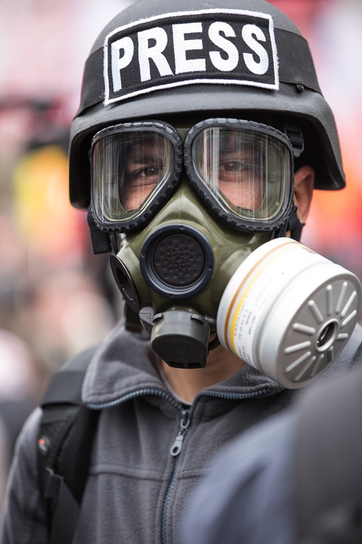A Journalist Live Reporting Wearing a Press Helmet and Gas Mask