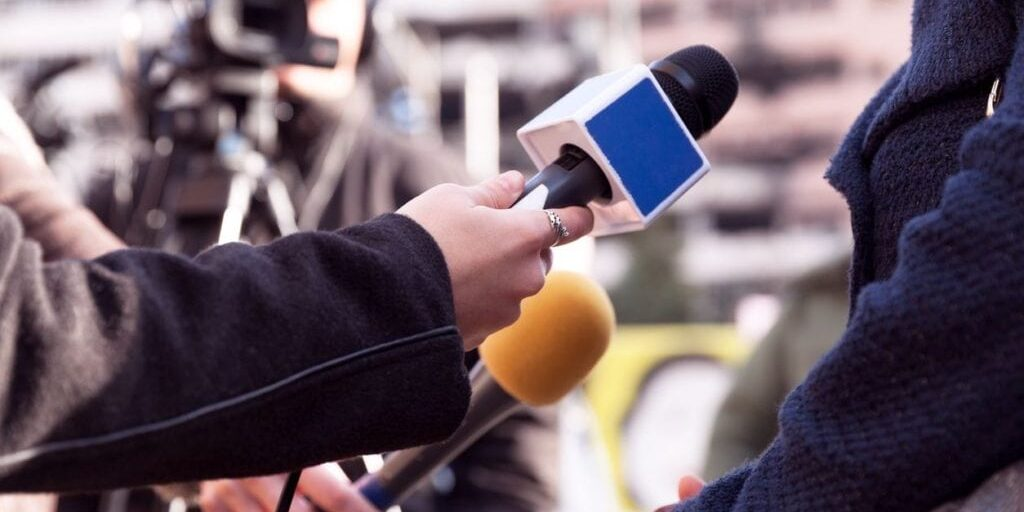 A journalist holding a mic to interview another person 