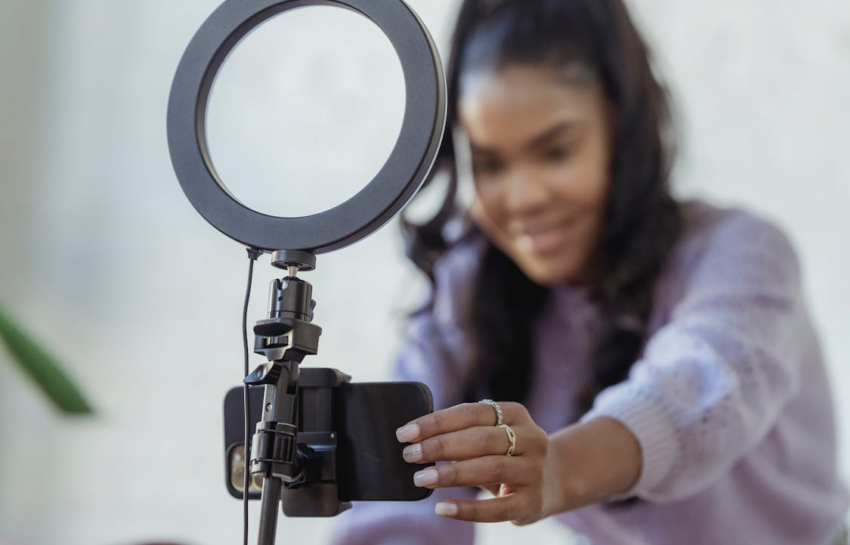 A young woman preparing to record on her smartphone by https://www.pexels.com/photo/happy-young-black-woman-setting-up-smartphone-before-shooting-podcast-6954220/